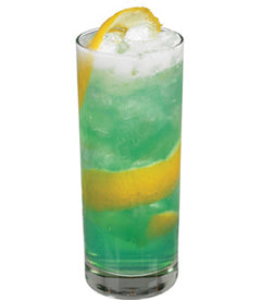 A bright green cocktail with ice is served in a tall glass with lemon slices visible inside and a lemon wedge on the rim