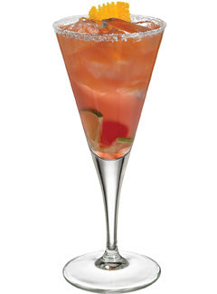 An orange-red cocktail with ice and visible citrus slices is served in a tall stemmed glass with a salted rim and garnished with an orange peel.