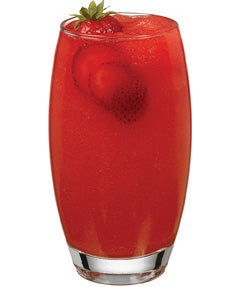 A bright red strawberry drink is served in a tall glass with strawberries visible inside and a whole strawberry with green leaves garnishing the rim.