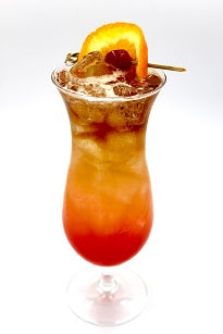 Hurricane glass with layered red orange and brown iced drink orange wheel cherry plain background