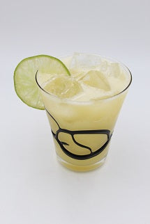 Rocks glass with pale yellow iced drink lime wheel plain background