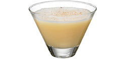 A pale yellow creamy cocktail with a smooth foamy top is served in a martini glass and lightly dusted with fine brown powder