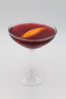 Coupe glass with red drink orange peel plain background