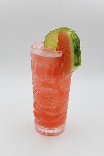 Tiki glass with pink iced drink lime wedge watermelon slice plain background