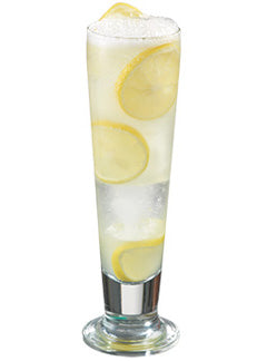 A clear pale yellow cocktail with ice and a foamy top is served in a tall stemmed glass with several lemon slices visible inside and on top