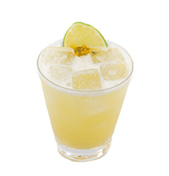 A pale yellow cocktail with ice is served in a short glass and garnished with a lime slice and a small citrus garnish on top
