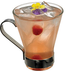 A pale peach-colored cocktail with ice and raspberries is served in a handled glass with a black base, topped with yellow and purple edible flowers.
