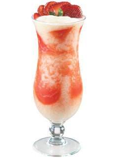 A pink and white strawberry cocktail is served in a tall stemmed glass with fresh strawberry slices and a creamy white topping on top