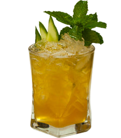 A golden-colored cocktail with crushed ice is served in a short glass and garnished with fresh mint leaves and green fruit wedges.