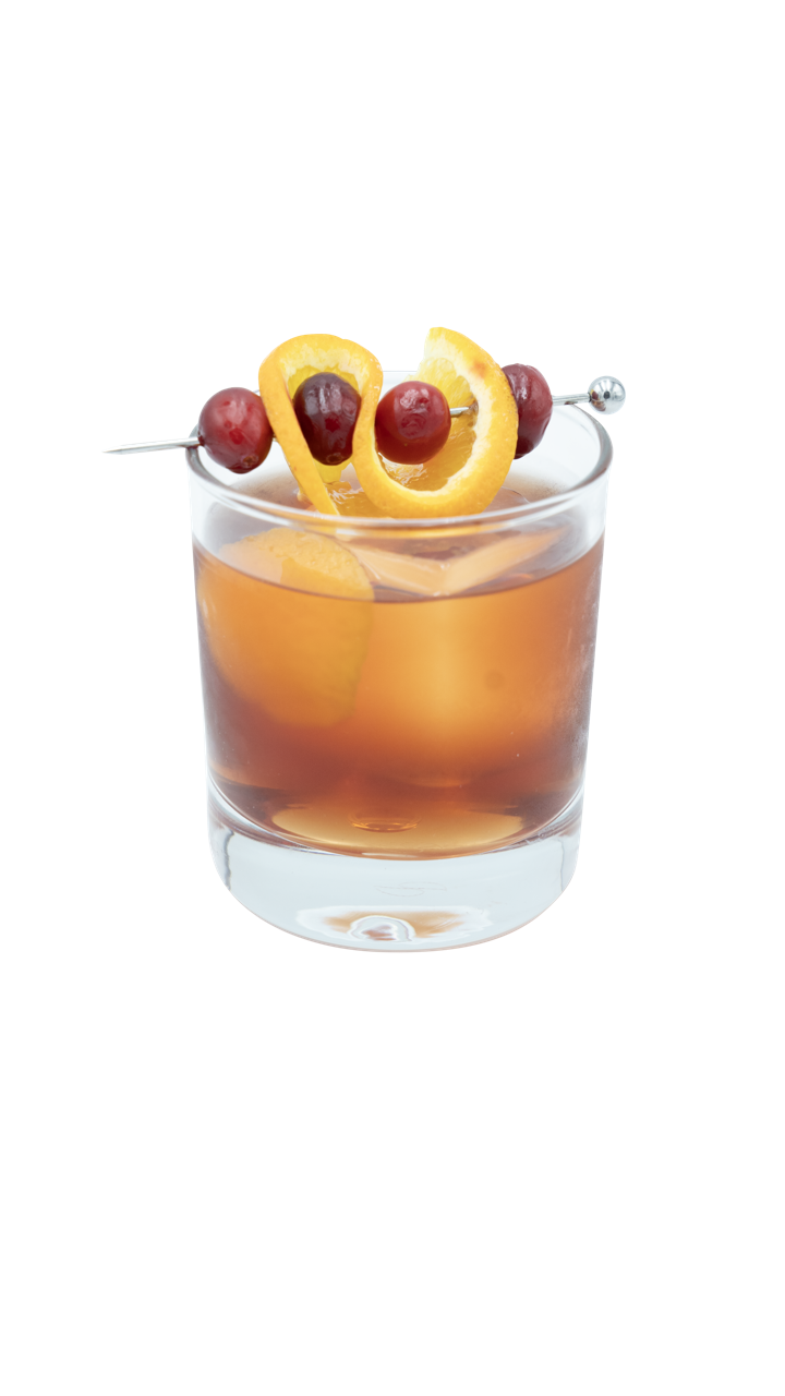 A golden brown cocktail is served in a short glass with ice and garnished with orange peel and cranberries on a cocktail pick.