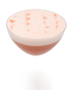 A pale pink cocktail with a thick white foamy top is served in a coupe glass, with small pink garnish pieces scattered across the foam.