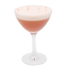 A pale pink cocktail with a thick white foamy top is served in a coupe glass, with a few small pink specks visible on the foam.