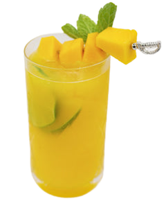 Yellow mango cocktail with ice lime pieces and mint garnish in a tall glass