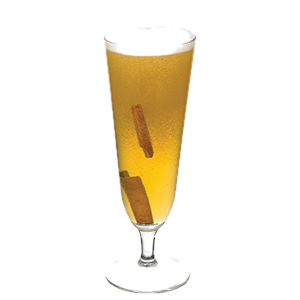 A golden cocktail with a white foamy top is served in a tall stemmed glass with two cinnamon sticks visible inside.