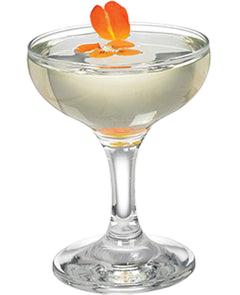 A pale green cocktail is served in a coupe glass and topped with a small orange flower garnish.