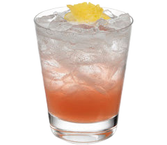 A pink-red cocktail with crushed ice is served in a short glass, with a yellow citrus garnish placed on top.
