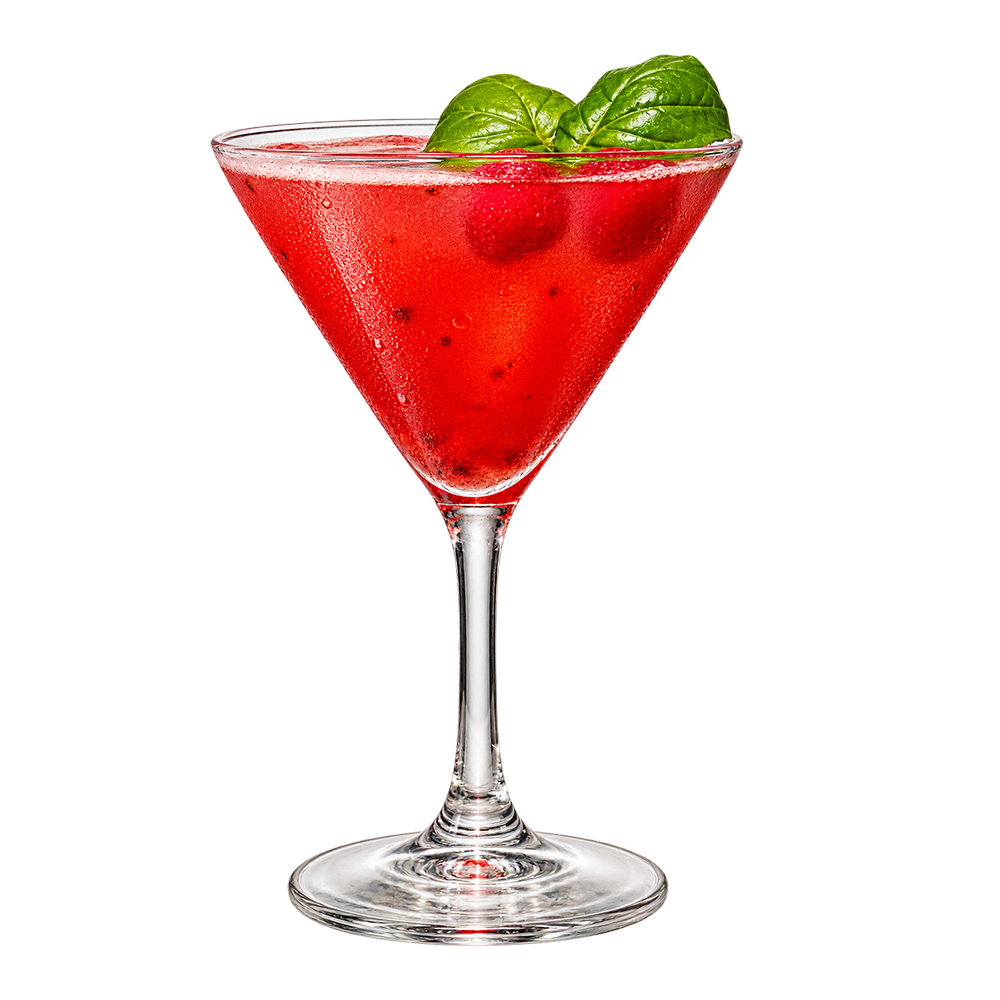 Martini glass with pink drink basil leaves plain background