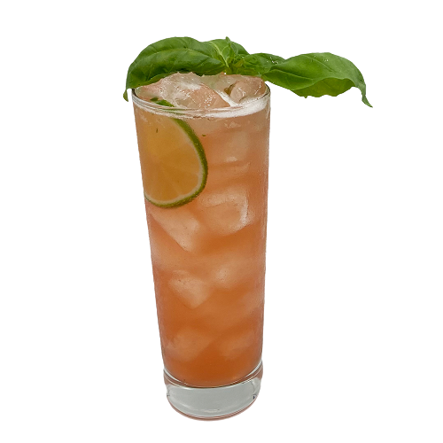 A pink-orange cocktail with ice is served in a tall glass with a lime slice inside and fresh basil leaves arranged across the top.