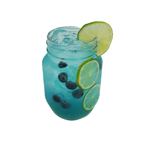 A bright blue cocktail with ice is served in a mason jar with blueberries and lime slices visible inside and a large lime slice on the rim